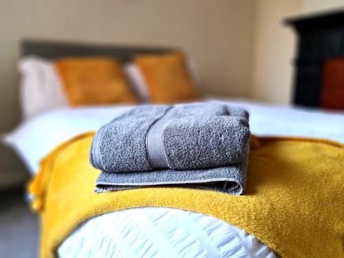 una pila de toallas sentadas en el borde de una cama en Ruby Retreat - Entire House - WiFi - 4 Bed - Garden - Maidstone Town, en Maidstone