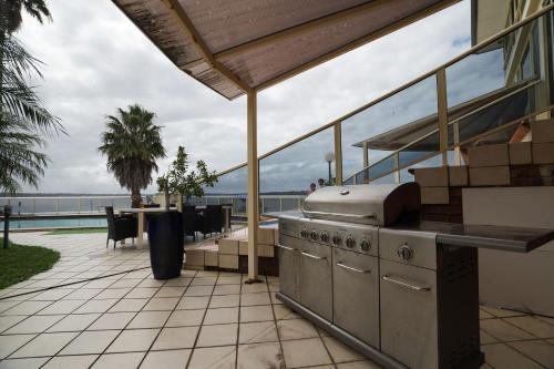 a patio with a grill and a table and chairs at Toukley Waterfront House in Toukley