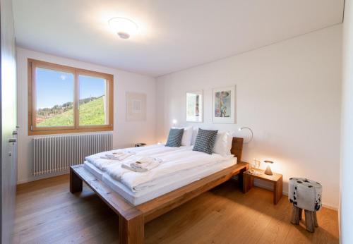 een witte slaapkamer met een groot bed met een raam bij Chalet Monchsbuffel in Wengen