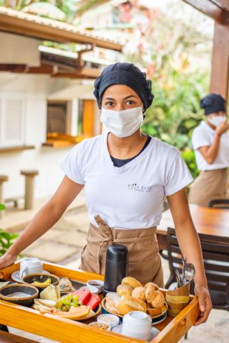 a woman wearing a mask standing in front of a table of food at Villa Sapê Pousada in Ubatuba