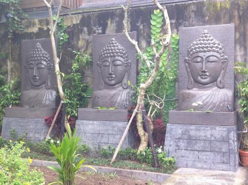 tres estatuas grandes sentadas en un jardín en Toko Toko Bungalows, en Ubud