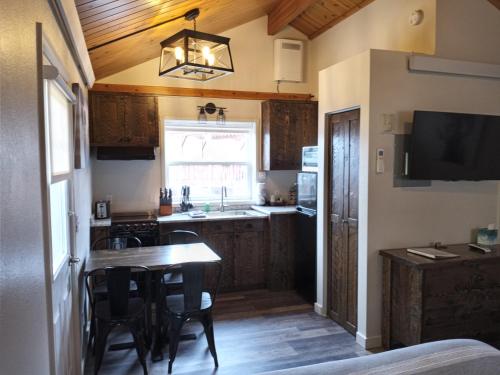 a kitchen with wooden cabinets and a table with chairs at Yellowstone Riverside Cottages in Gardiner