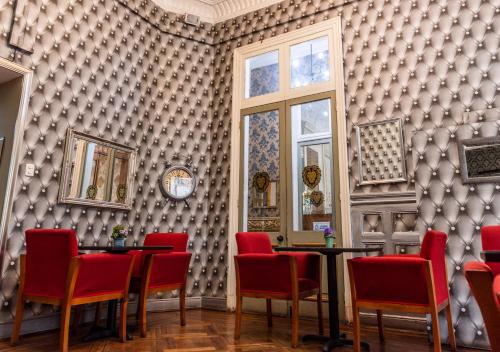 a dining room with red chairs and a wall of wallpaper at Hotel Casa Zañartu in Santiago