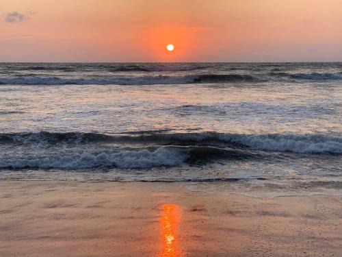 a sunset on the beach with the ocean at casa munay in Canoa