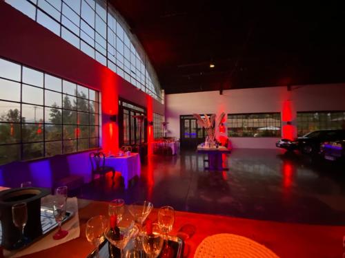 Strip Center Suites by Casona Lo Aguirre في El Monte: غرفة بها أضواء حمراء وكؤوس للنبيذ على طاولة