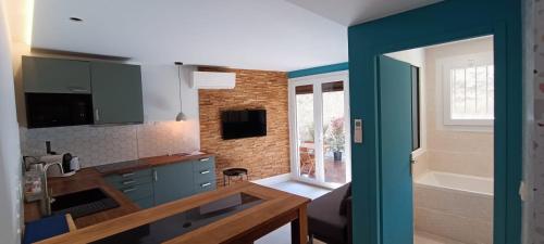 a kitchen with blue cabinets and a bathroom with a tub at Superbe T2 avec grande terrasse en centre ville à 5 min à pieds des Arènes de Nîmes in Nîmes