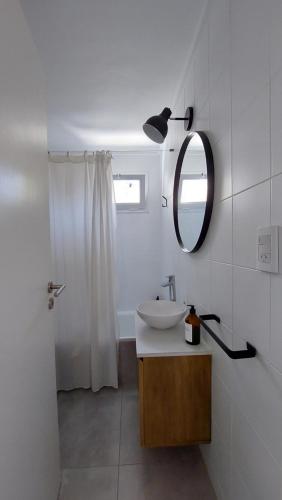 a white bathroom with a sink and a mirror at ONE Departamentos in Tandil