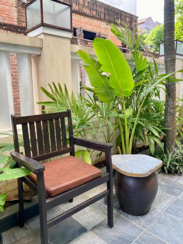 a wooden chair sitting on a patio with plants at The Quin Riverside Villa in Hoi An