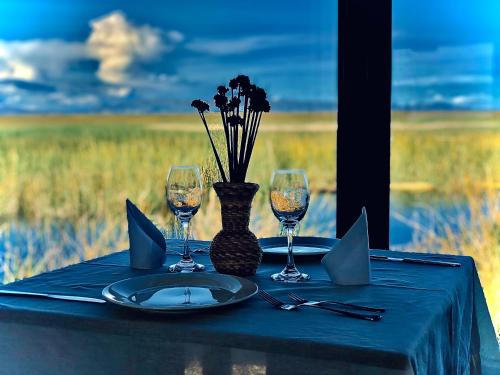 a table with wine glasses and a vase with flowers at Titicaca Ecolodge Perú in Puno