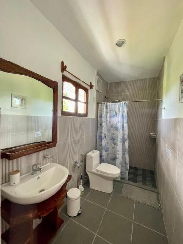 a bathroom with a sink and a toilet and a mirror at Agoho Resort in Mambajao