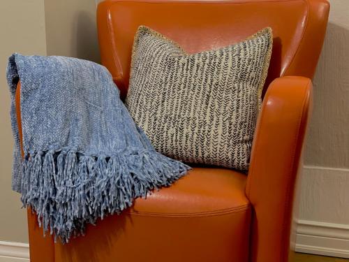 a blanket on a orange chair with a pillow at The Loft at Charlotte's Rose in Charlottetown