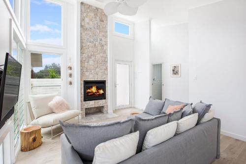 a living room with a couch and a fireplace at Unwind Pet Friendly 1 Min Walk to Beach in Culburra Beach