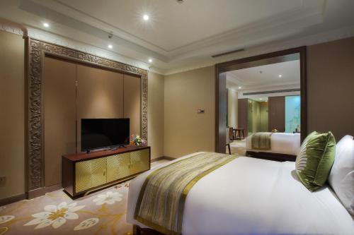a bedroom with a large bed and a television at Mekong River Jing Land Hotel in Jinghong