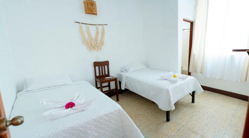 a bedroom with two beds with white sheets and flowers on them at Casa Ramona in Flores