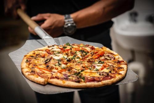 a person holding a pizza on top at Royal Hotel Mandurama in Mandurama