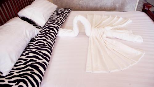 a white bed with a zebra print sheets and pillows at Stusky Lark Mini Hotel Seeta in Seeta