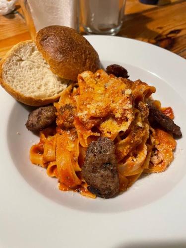 a plate of pasta with sausage and bread on a table at Vela Terraces Hotel in Coron