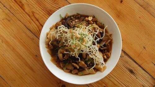 a bowl of pasta with mushrooms and cheese on a table at Vela Terraces Hotel in Coron