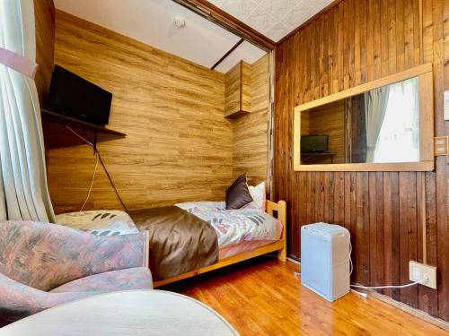 a small room with two beds and a tv at Kominka Okinawa in Okinawa City