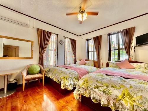 a bedroom with two beds and a table and a fan at Kominka Okinawa in Okinawa City