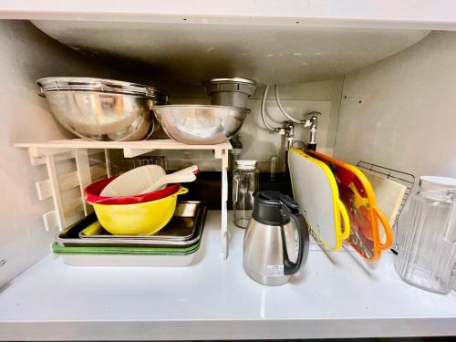 a kitchen with some bowls and pans on a shelf at Kominka Okinawa in Okinawa City