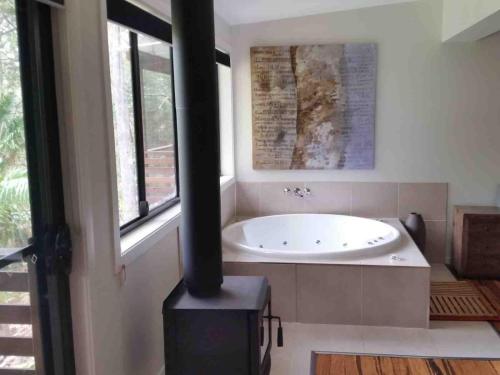 a bathroom with a bath tub and a stove at Alaya Escape in Eudlo