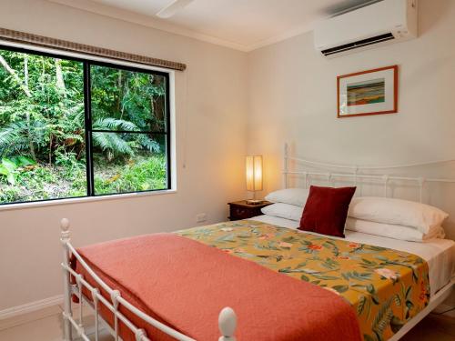 a bedroom with a bed and a large window at Honeybee House in Kuranda