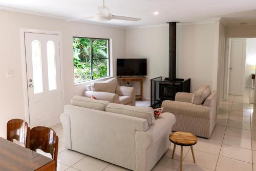 a living room with two couches and a tv at Honeybee House in Kuranda