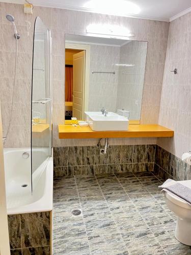 a bathroom with a sink and a toilet and a mirror at Nautica Hotel Apartments in Stavromenos