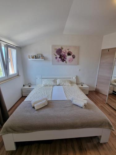 - une chambre avec un grand lit et 2 serviettes dans l'établissement Apartment Tena, à Privlaka