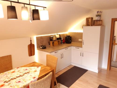 a kitchen with a table and a white refrigerator at AnNo - Wohlfühlen am Bachal in Altschönau in Neuschönau