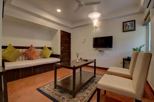 a living room with a couch and a table and a tv at Elite Hotel in Lonavala