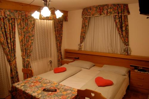 Un dormitorio con 2 camas y una mesa con almohadas rojas. en Albergo Genziana, en San Vigilio Di Marebbe