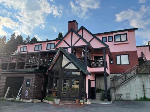 a large pink house with a balcony at アルパインロッジ in Inawashiro