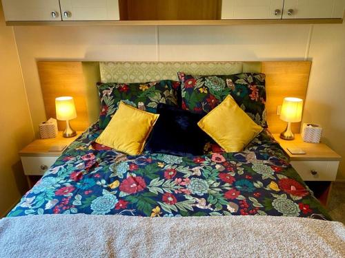 a bed with a colorful comforter and two lamps at Ocean Edge Holiday Park Family holiday home with spectacular sea views in Heysham