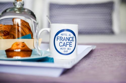 a coffee cup and a plate of food on a table at Logis Hotel de France in Mimizan-Plage