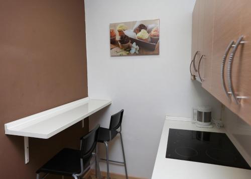cocina con encimera blanca y 2 sillas negras en Apartaments Olivier Barcelona, en Barcelona