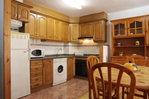 a kitchen with wooden cabinets and a table and a white refrigerator at Apartamentos Los Tilos in Benasque