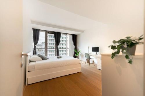 a white bedroom with a bed and a window at Lux City Hamilius - Modern & Spacious Apart w/View in Luxembourg