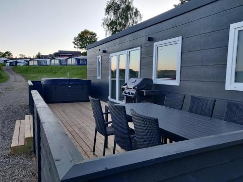 a deck with a grill and chairs on a tiny house at Terrassen Camping & Cottages in Silkeborg