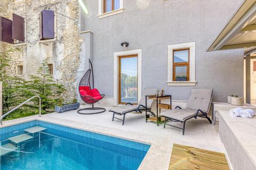 a pool with two chairs and a red chair next to a house at Holiday House Lidia i Rina in Pićan