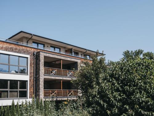an apartment building with balconies and a tree at Village Park Suites by VAYA inklusive Zell am See Kaprun Sommer Karte in Zell am See