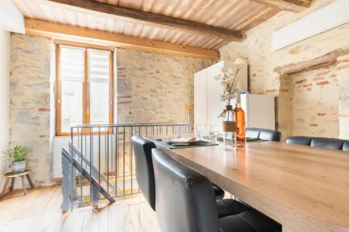 une salle à manger avec une grande table en bois et des fauteuils en cuir dans l'établissement Gîte Tour du Rocher, à Luzech