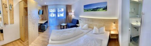 a hotel room with a white bed and a bathroom at Alpenrose Appartements in Nesselwang