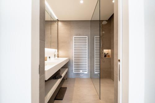 a bathroom with a sink and a glass shower at Lux City Hamilius - Modern & Spacious Apart w/View in Luxembourg