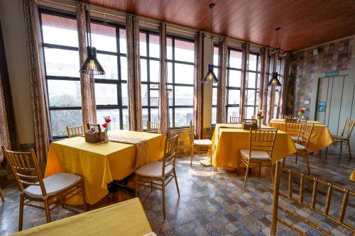 un restaurante con mesas y sillas amarillas y ventanas en HOTEL MITTAL GARDEN, en Siliguri