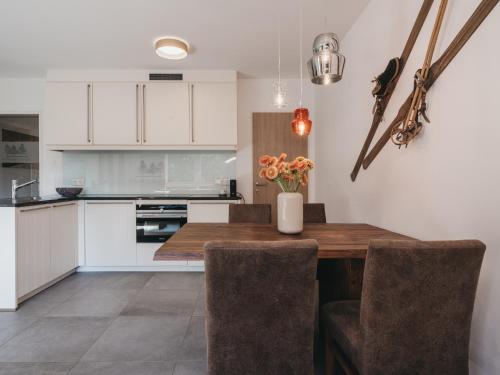 a kitchen with white cabinets and a wooden table with chairs at Village Park Suites by VAYA inklusive Zell am See Kaprun Sommer Karte in Zell am See