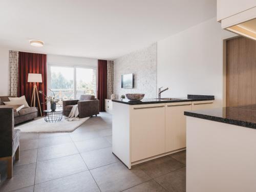 a kitchen with white cabinets and a living room at Village Park Suites by VAYA inklusive Zell am See Kaprun Sommer Karte in Zell am See