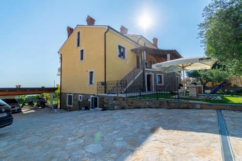 a large yellow house with a patio and an umbrella at Apartments Apartim Piran in Piran