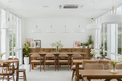 a dining room with tables and chairs and windows at Casa 33 Hatyai in Hat Yai